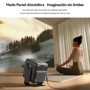 Una persona meditando frente a una proyección de un bosque nevado de montaña en una pared de sala de estar. Un proyector Wanbo Mozart 1 Pro de color gris oscuro está en el primer plano, proyectando la imagen. El texto en la parte superior habla del "Modo Pared Atmósfera". Una nota al pie dice que el soporte no está incluido.