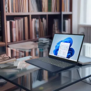 Equipo portátil sobre escritorio de cristal en un entorno de oficina moderna